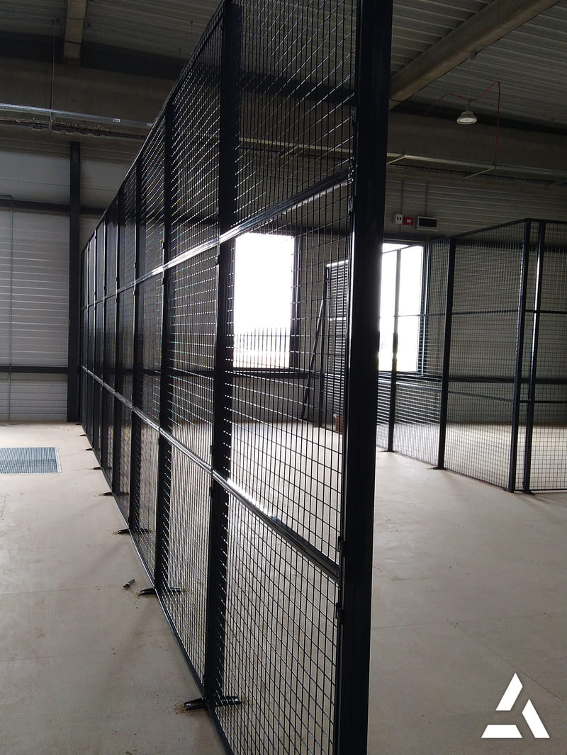 Cloisons grillagées métalliques noires en entrepôt, séparation sécurisée des espaces de stockage et de circulation