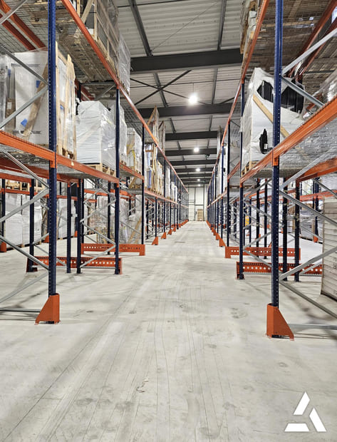 Allee d’entrepot avec rayonnages a palettes metalliques charges, stockage logistique optimise pour palettes et marchandises
