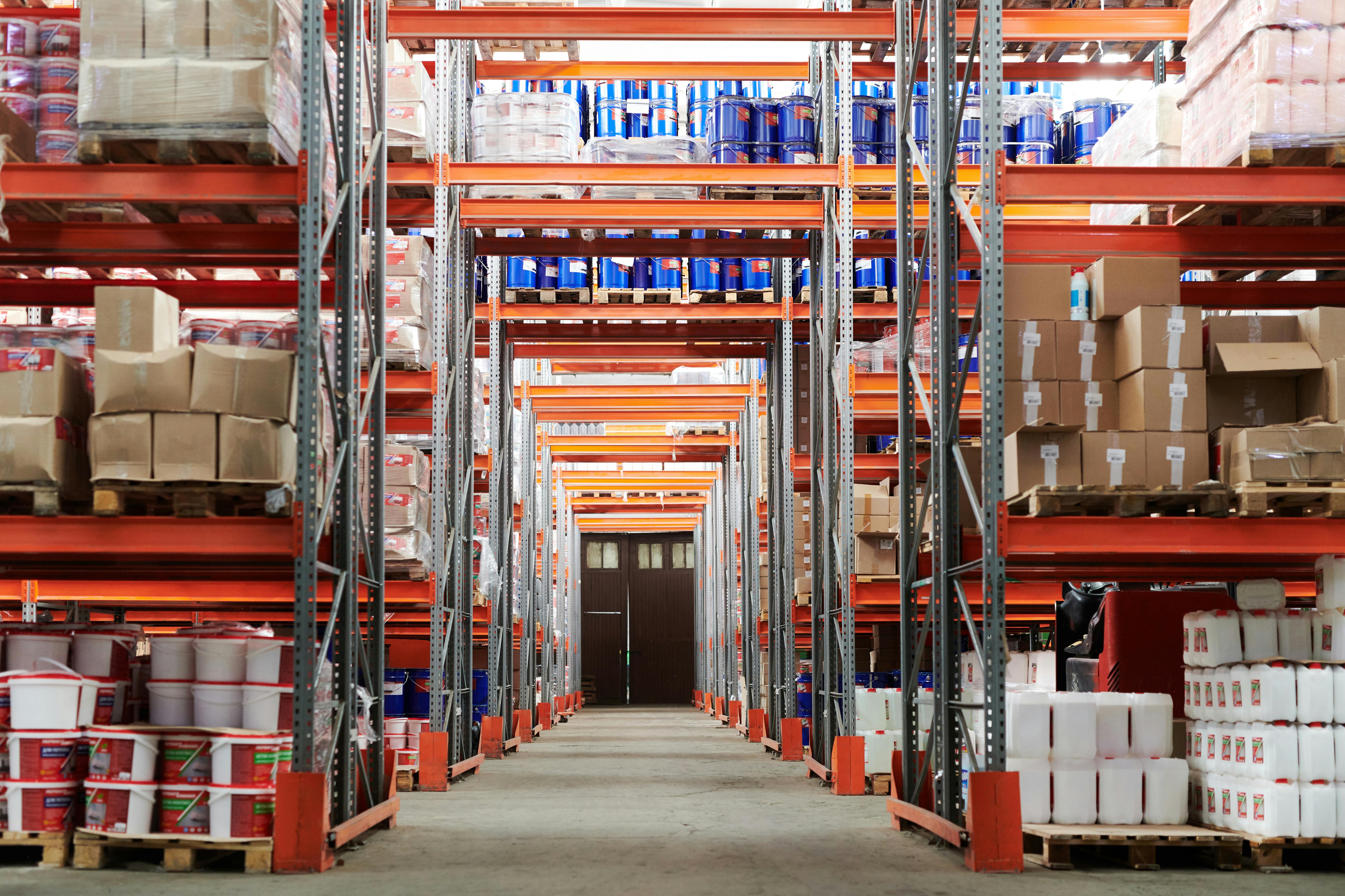 Allée vide d’un entrepôt de stockage industriel avec rayonnages remplis de cartons et contenants
