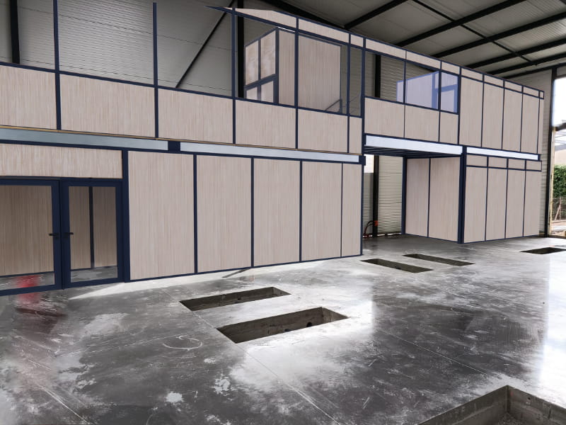 Mezzanine industrielle avec bureaux modulaires en bois et structure métallique dans un entrepôt moderne en cours d’aménagement