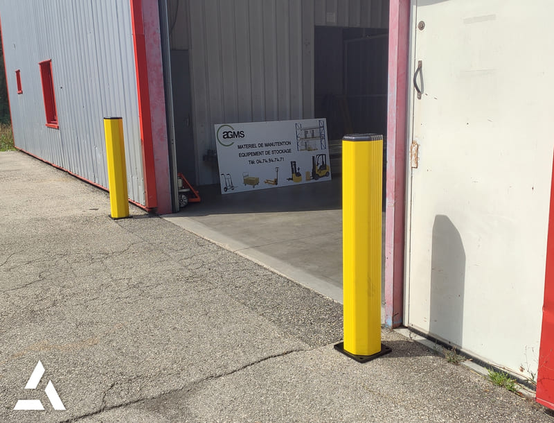 Poteaux de protection jaunes installés a l'entrée d'un bâtiment pour sécuriser accès et circulation
