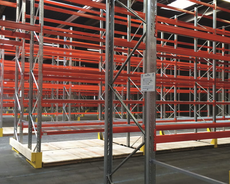 Rayonnage industriel en acier avec lisses rouges dans un entrepot logistique, structure de stockage pour palettes et marchandises