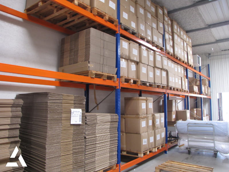 Rayonnages industriels avec palettes et cartons stockés en hauteur dans un entrepôt logistique organisé