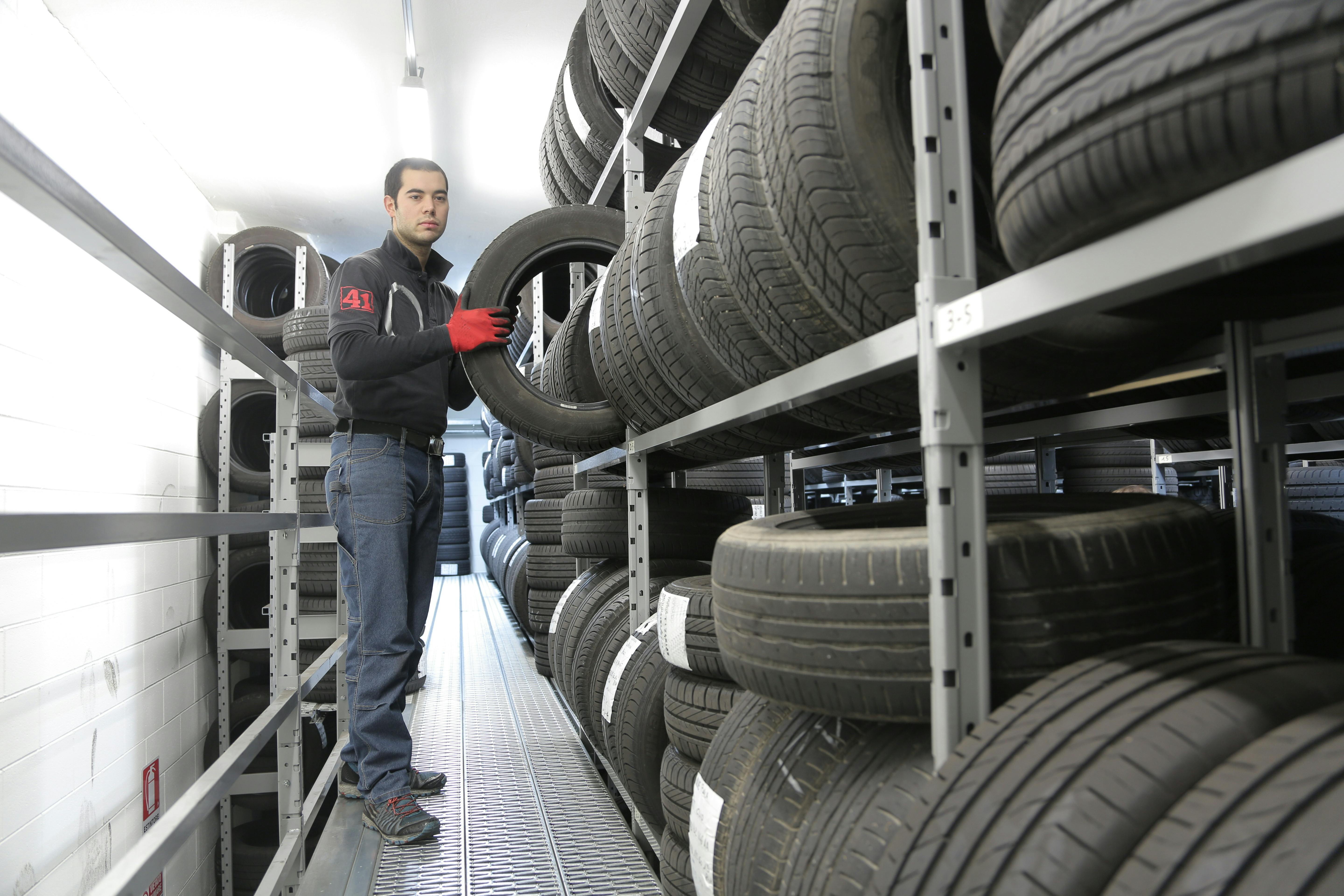Employé rangeant des pneus dans un entrepôt de stockage automobile